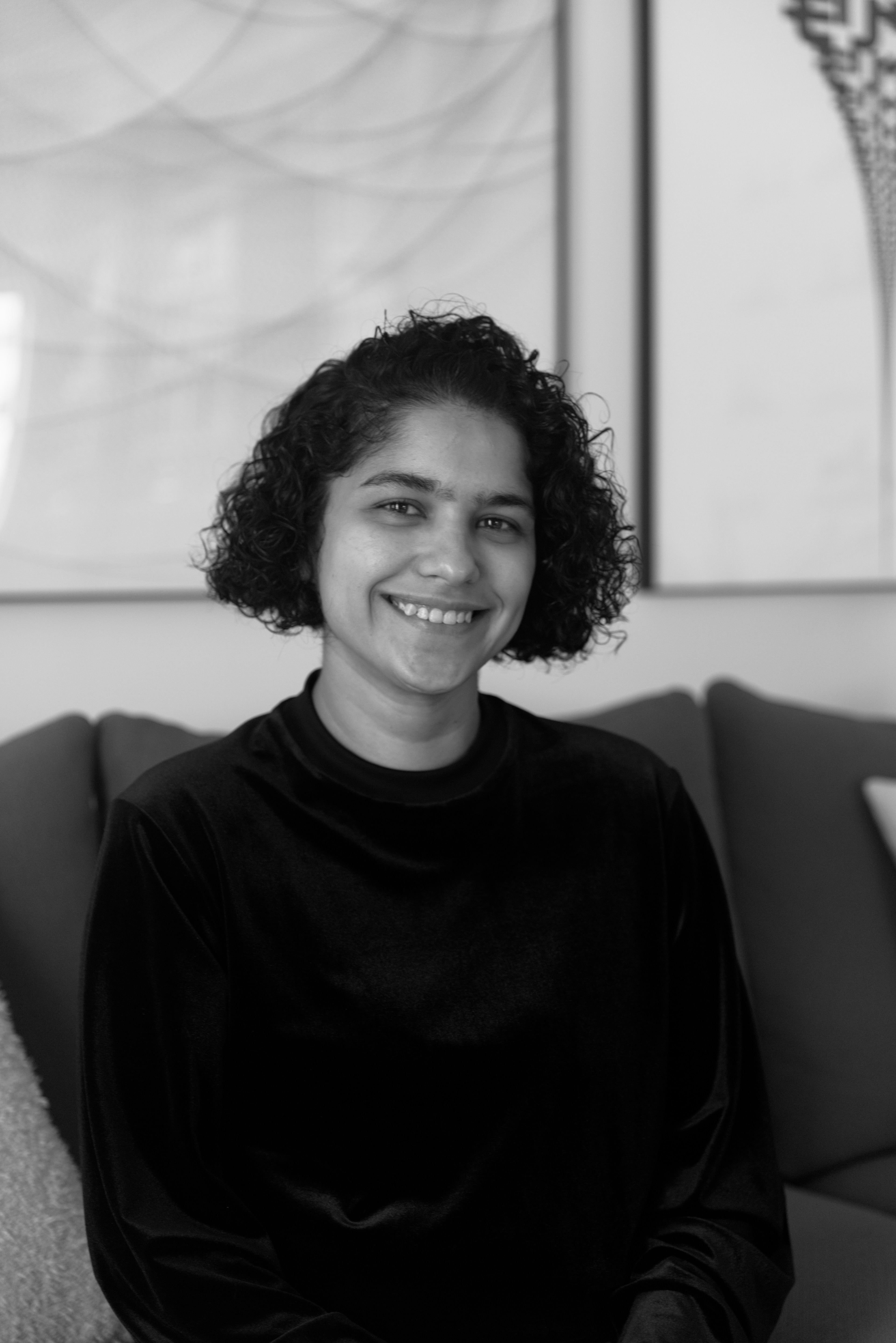 Rekha Tenjarla smiling, seated on a couch